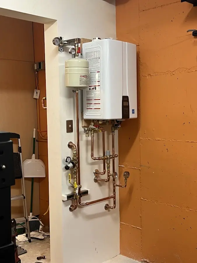 Plumbing technician inspecting water heater connections in East Allen